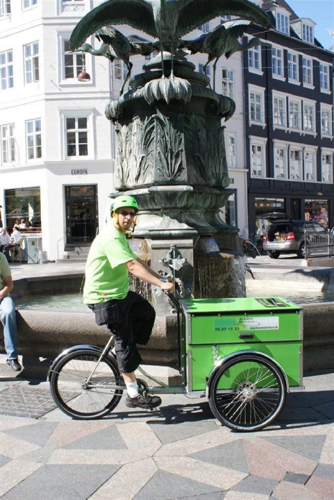 Grøn elektriker cykler rundt i København En Grøn Elektriker på en elcykel i København ved springvand